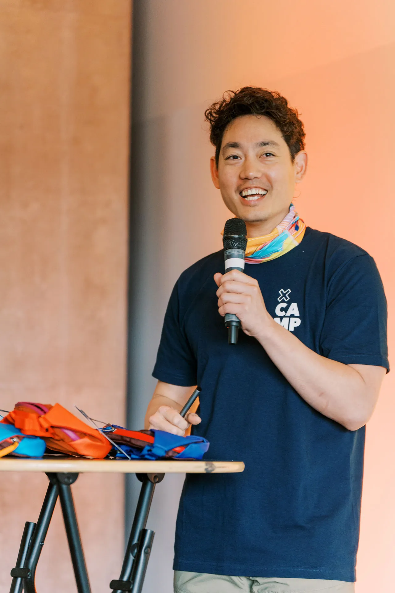 Albert Jame with a mic in hand, speaking, and smiling