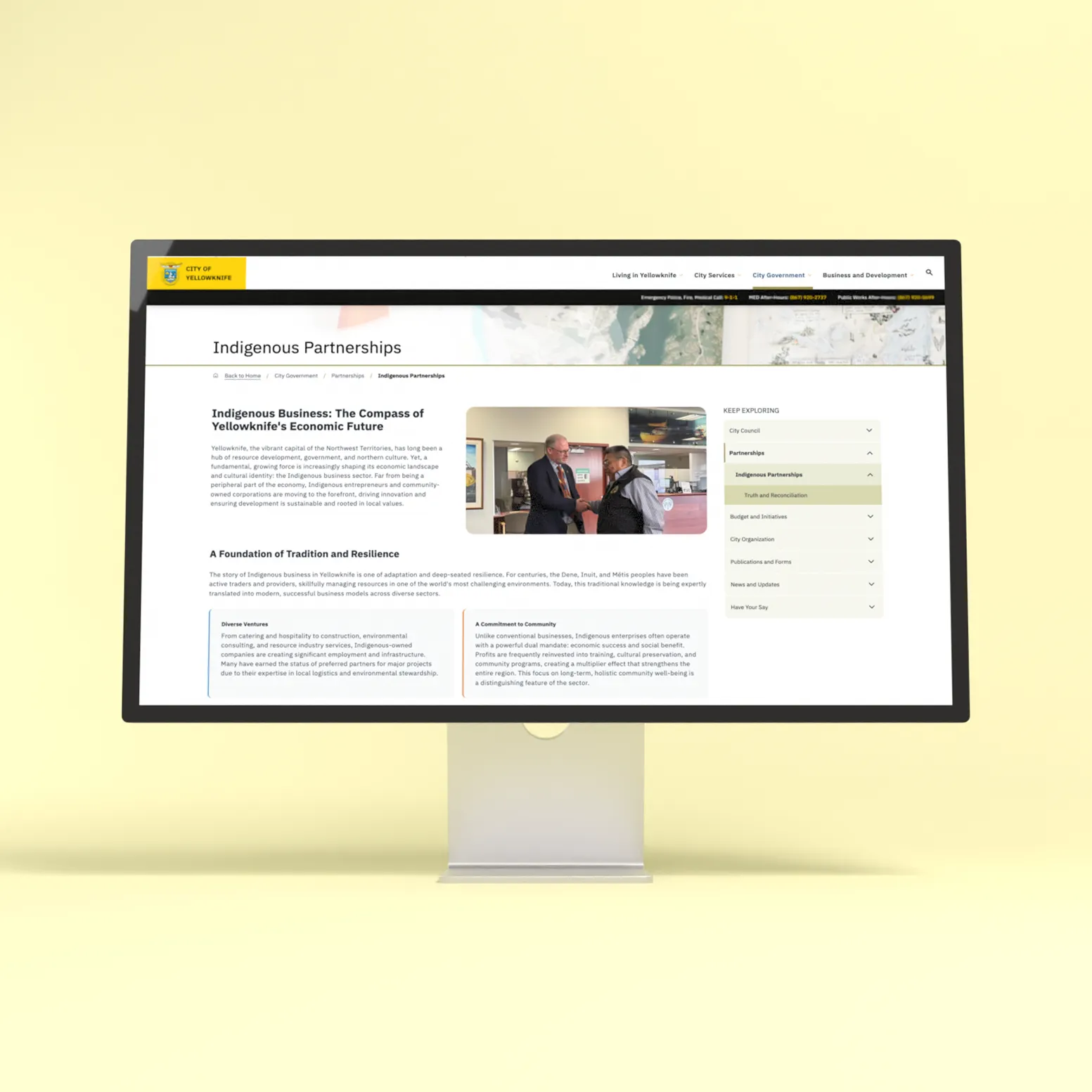 Desktop monitor displaying the City of Yellowknife Indigenous Partnerships page on a yellow background