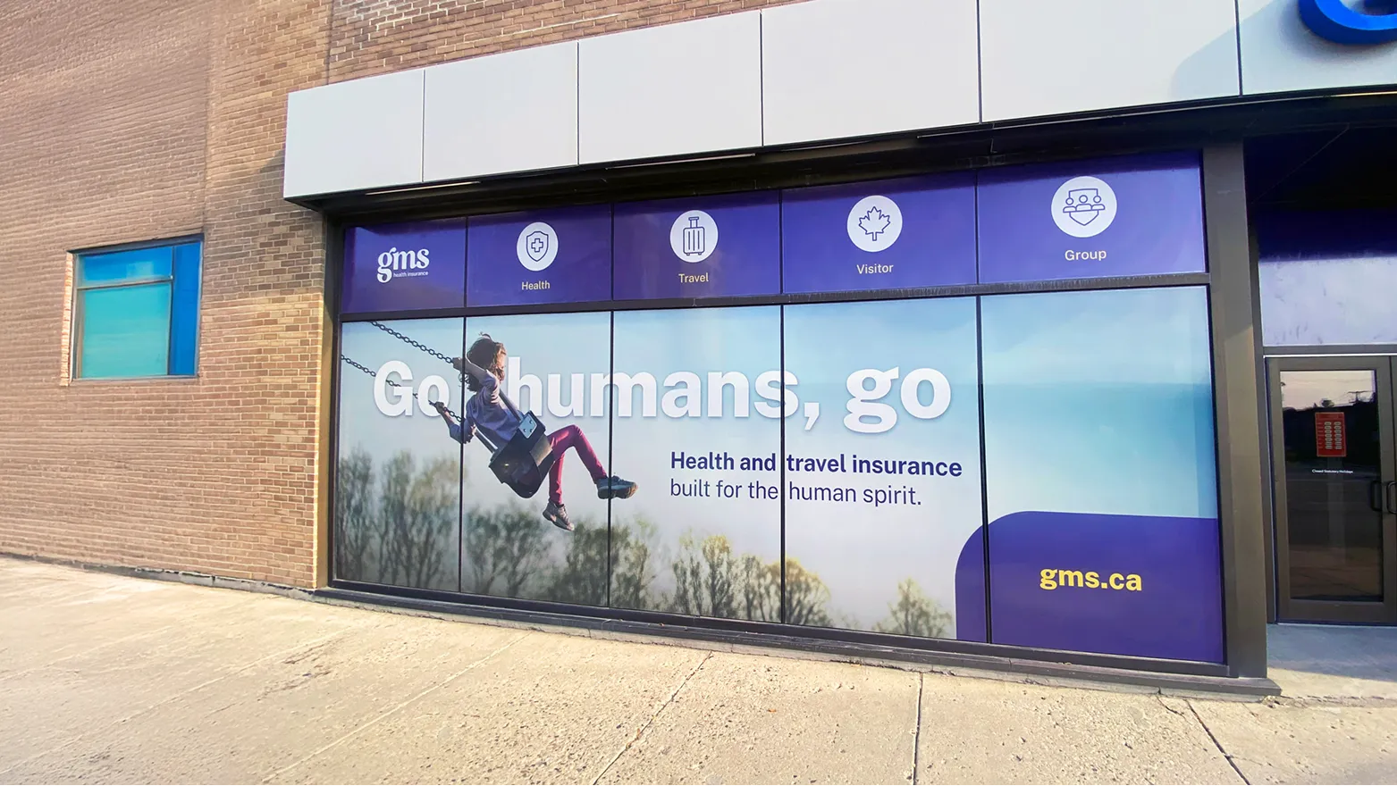 Building storefront wrapped with GMS window graphics and Go humans, go campaign