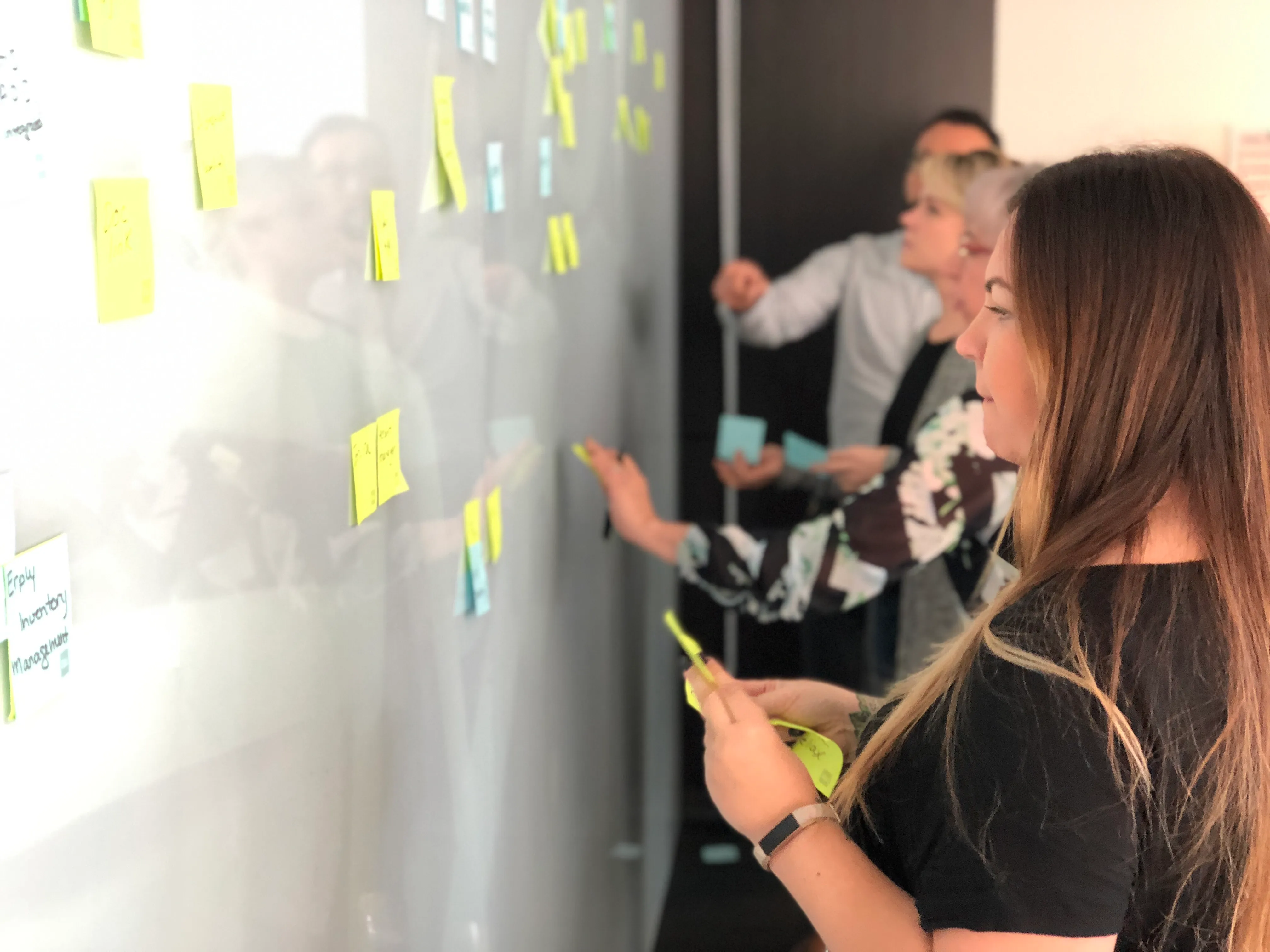 People putting sticky notes on a board.