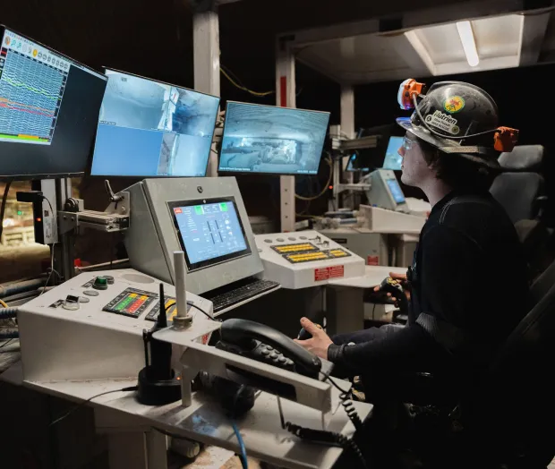 An operator wearing a hard hat using the interface at a control station.