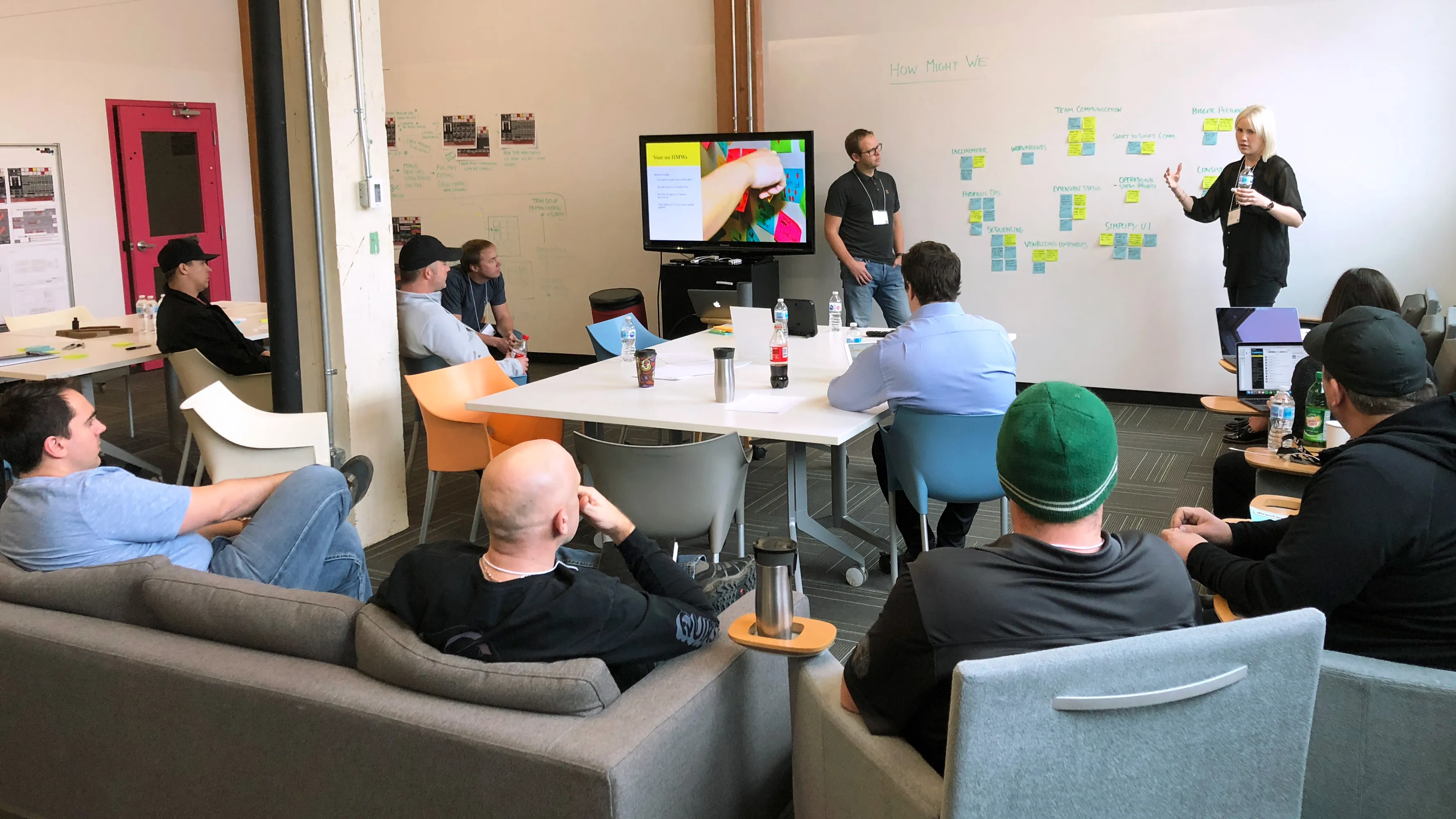 Team members sketching interface ideas and reviewing printed wireframes at a workshop table