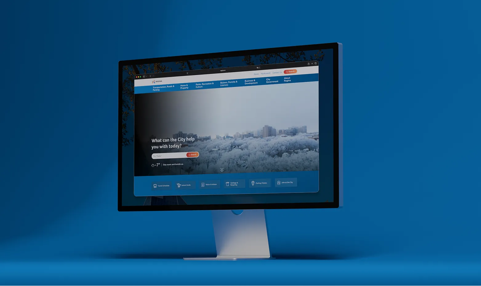 Desktop monitor mockup displaying the City of Regina website homepage on a blue background