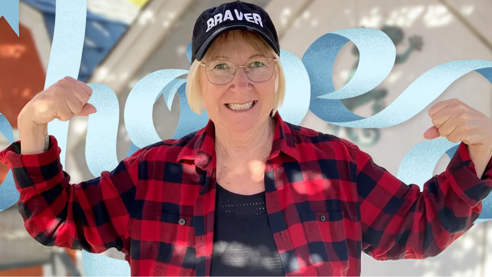 Portrait of a cancer survivor raising both arms in front of large 'hope' lettering