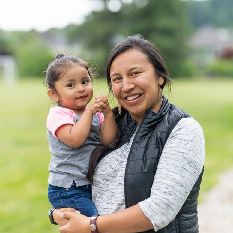 Smiling woman holding a young child outdoors